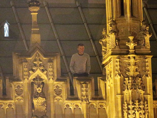 Foto tirada neste sábado (7) mostra jovem de 23 anos no telhado do Parlamento, em Londres (Foto: Yui Mok/PA Wire/AP)